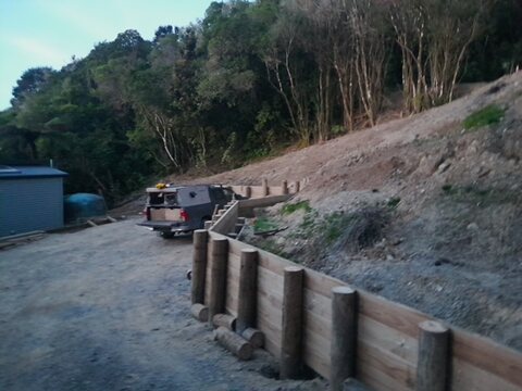 Completed timber retaining wall holding a steep bank above a driveway