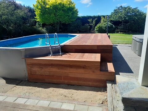 Pool deck with wide timber steps down to the paving