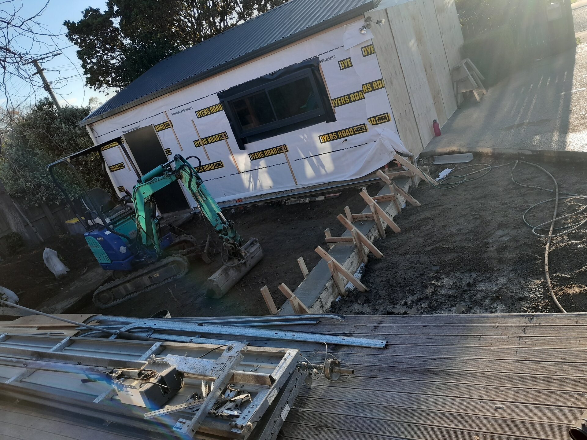 Relocated house being set down onto new foundations with a digger alongside