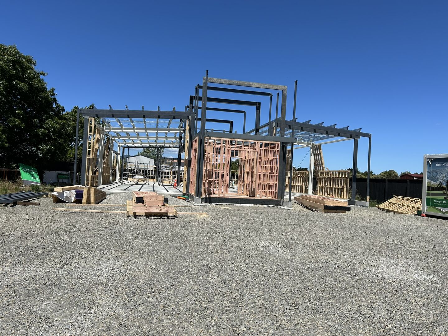 Steel portal frame with rafters and purlins standing on a concrete slab, with braced timber wall framing panels stood up along one side