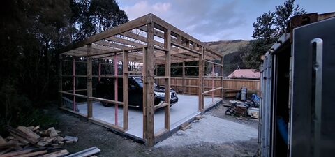 Timber garage frame on a fresh concrete slab with hills behind