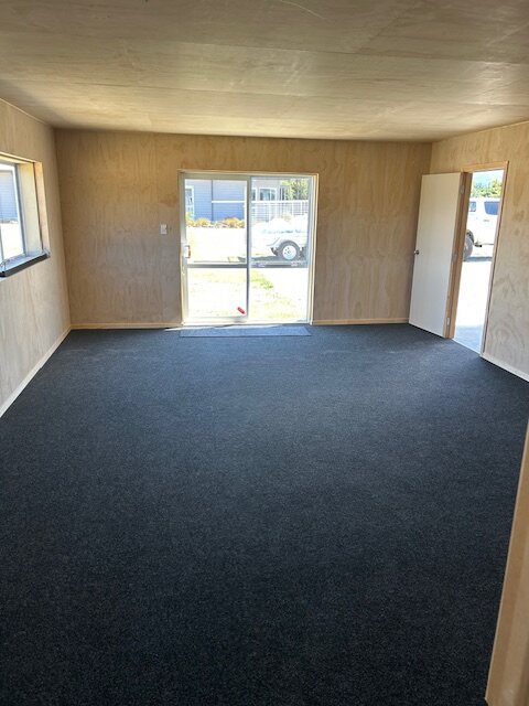Plywood-lined shed interior with carpet and a glazed sliding door