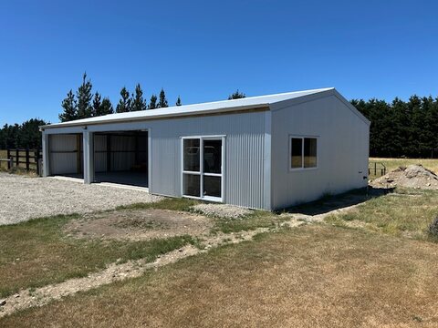 Completed rural shed with open bays, roller doors and a personnel window