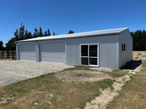 The same shed with roller doors closed, gravel apron in front