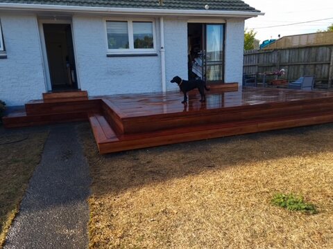 Finished hardwood deck and steps running off a white weatherboard house