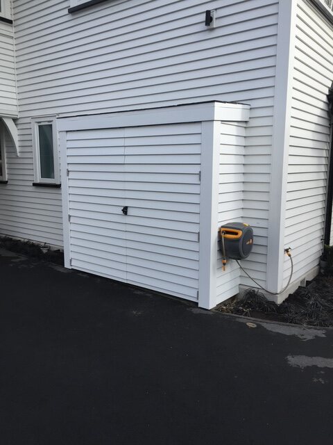Weatherboard bin store closed, matching the house cladding and paint