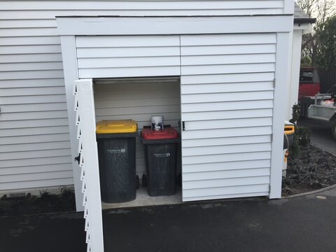 The bin store with its door open showing the wheelie bins inside